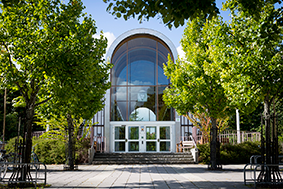 A building with big glass windows surrounded by trees. Photo.